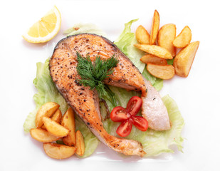 A dinner of fried fish, chips, french fries, served with a fresh salad , tomato and a the piece of lemon