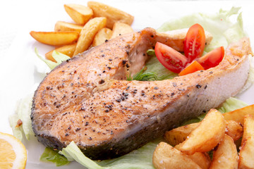 A dinner of fried fish, chips, french fries, served with a fresh salad , tomato and a the piece of...