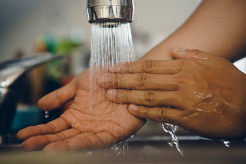 Cropped shot of an unrecognizable man washing his hands  at home to prevent spreading of the coronavirus ( Covid-19)