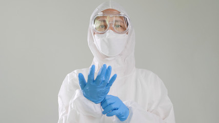 Asian doctor in protective hazmat PPE suit wearing medical latex gloves