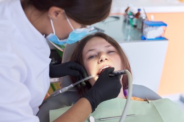 Woman doctor dentist treating teeth to girl patient in dental office