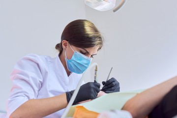 Naklejka premium Woman doctor dentist treating teeth to girl patient in dental office