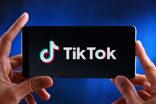 Hands holding smartphone displaying logo of TikTok