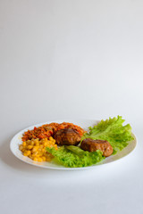 Fried chicken cutlet with potato slices served with tomato cherry and corn salad. Traditional belorussian food - roasted minced meat and potato