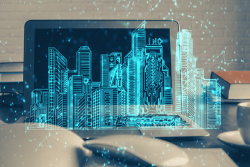 Desktop computer background in office and big town buildings hologram drawing. Double exposure. Smart city concept.