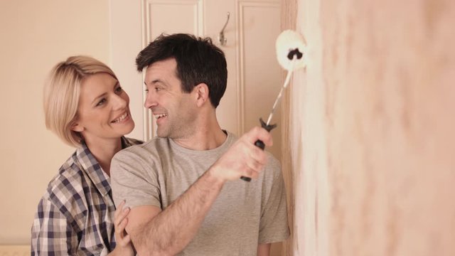 Adult couple painting wall in new home