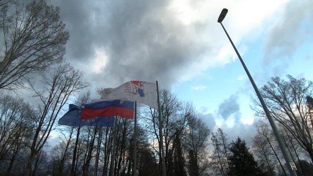 Slow motion dynamic moving looking up European, Slovenian and State Protocol Services of Slovenia flags waving in wind