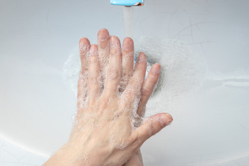 Top above close up view woman standing in bathroom washing her hands under flowing water flushing soap. Stop corona virus covid19, keep personal hygiene, infectious pandemic disease prevention concept