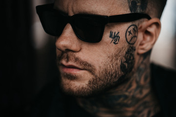 Portrait eines jungen muskulöser Mannes mit Tattoos und Sonnenbrille 