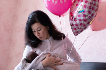 Young grandmother holding baby sitting on bed. Young beautiful grandmother spends time with newborn...