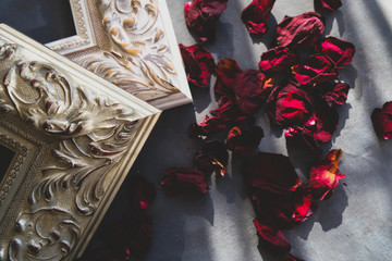 Corners of classic wooden picture frames and rose petals. Ornamental vintage art frames on grey canvas backdrop.