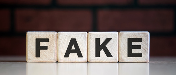 Fake - text on wooden blocks, dark background