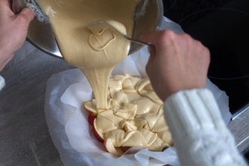 The hostess prepares apple charlotte at home in the kitchen and pours the dough into a baking dish