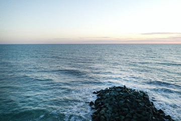 Nordseebuhne mit Wellen und vielen grossen steinen zum sonnenuntergang