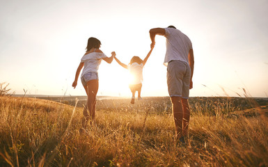 Happy family walking in nature at sunset in summer.