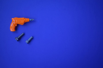 .children's orange drill on a blue background and two gray bolts