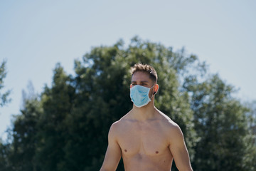 Portrait of a gorgeous guy wearing a mask to avoid contagion while walking down the street. Coronavirus concept