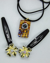 Two hairpins decorated with flowers and a pendant on a black tesme