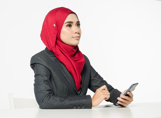 Communication concept, young woman with hijab sitting and texting her friends using her handphone against white background