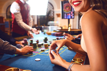 Chips in the hands of a female roulette player in casino background.