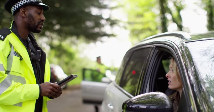 4K Fed up female driver giving her details to traffic cop with a computer tablet. Slow motion.