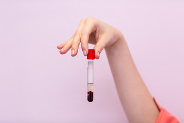 Laboratory assistant in medical laboratory holds test tube with blood and plasma in his hand and...