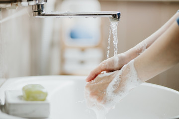 Closeup of a woman washing her hands in bathroom to prevent Covid-19 viral infection. Recommended...
