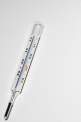 Analog mercury in glass thermometer on white surface with copy space on right side. Clinical thermometer for measuring fever