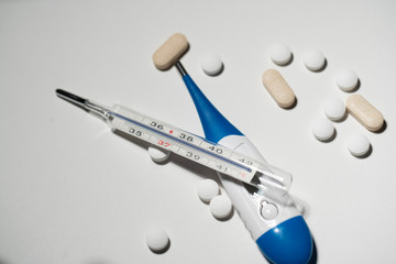 Mercury fever thermometer on a digital clinical thermometer for measuring fever, different pills and medicine. Analog writings on thermometer