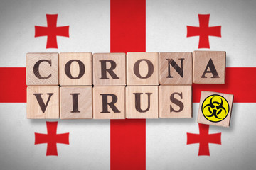 Georgia flag background and wooden blocks with letters spelling CORONAVIRUS and quarantine symbol on it. Novel Coronavirus (2019-nCoV) concept for an outbreak occurs in Georgia.