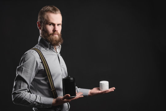Handsome young man presents car parts on a gray background. The concept of sales and testing of goods
