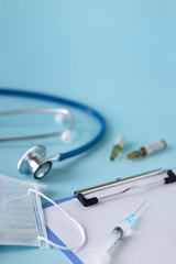 medical concept on a blue background. stethoscope, pills, tablet, notepad, sheet of paper, pen. Medical mask. Copy space
