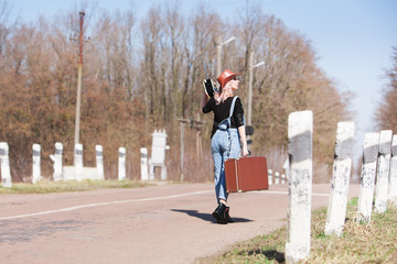 Young traveling woman with a suitcase walking on the road