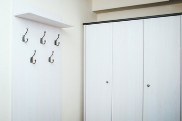 White hallway storage cabinet with hangers and closet. Minimalist design furniture.