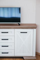 Tv set on a modern white drawer chest.