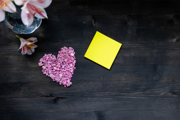 Background Valentine's day - pink heart flowers yellow square piece of paper for notes on a dark background