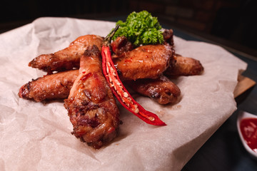 Appetizing fried chicken wings on a wooden tray. Studio photography of food in the cooking industry, dark background