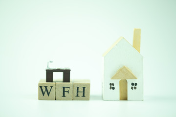 Text of WFH mean work from home with miniature table and wood home.