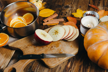 Close-up of ingredients for cooking mulled wine. Cutted apples on a wooden board, oranges, cinnamon...