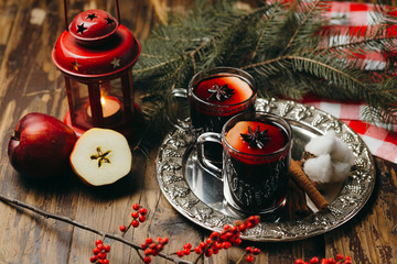 Two cups with mulled wine with cinnamon on silver tray and an orange and fur-tree branches, a New Year's still-life.