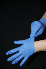  Putting on blue gloves, on black background