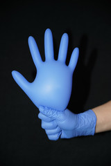 Blue gloved hand, holding another surgical glove inflated with air	