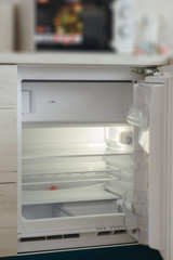 A picture of an open empty fridge and a microwave on it. Kitchen close up.
