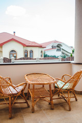 Table and two wicker chairs and the rooftop view from the outdoor terrace.