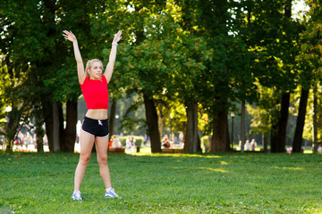 A young blonde girl is engaged in sports in the park, a woman does a warm-up in the street. Active outdoor training