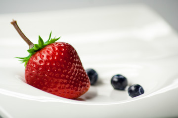 Erdbeere und Heidelbeeren auf weißem Teller