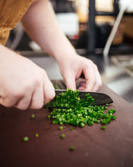Chef cuts green onions in a restaurant kitchen