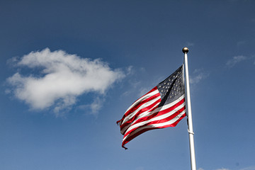 american flag waving in the wind against blue sky