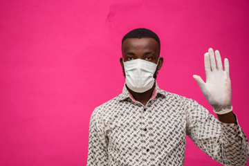 a young african doctor isolated over pink background wearing face mask to prevent himself from the...