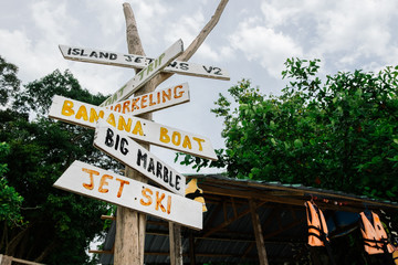 pieces of wood with hand painted beach activities attached to tree stump in Pangkor Island, Perak State, Malaysia